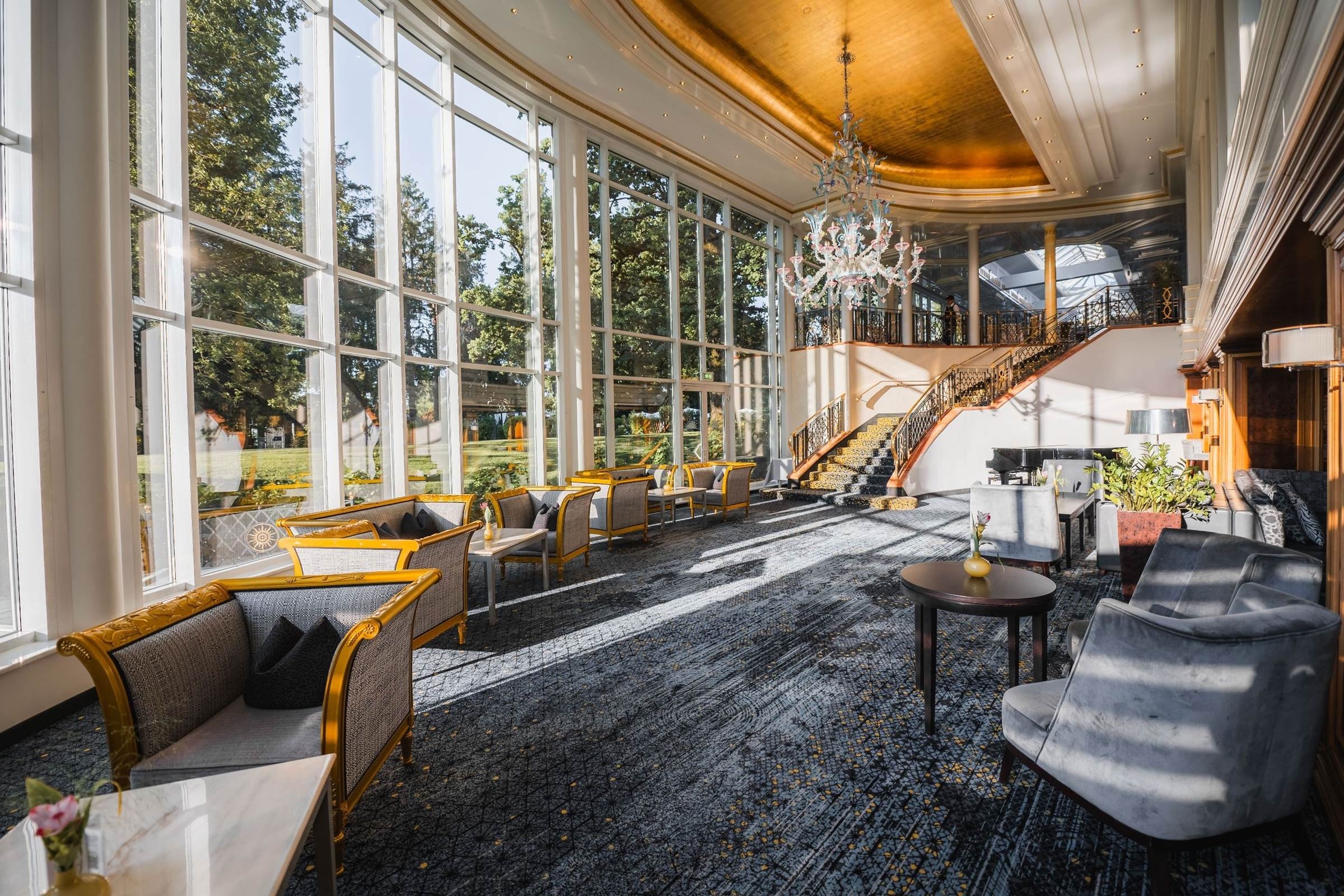 Lichte Lounge mit Murano-Kronleuchter und Blick in den Park